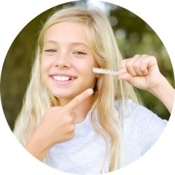 young girl holding invisalign clear aligners